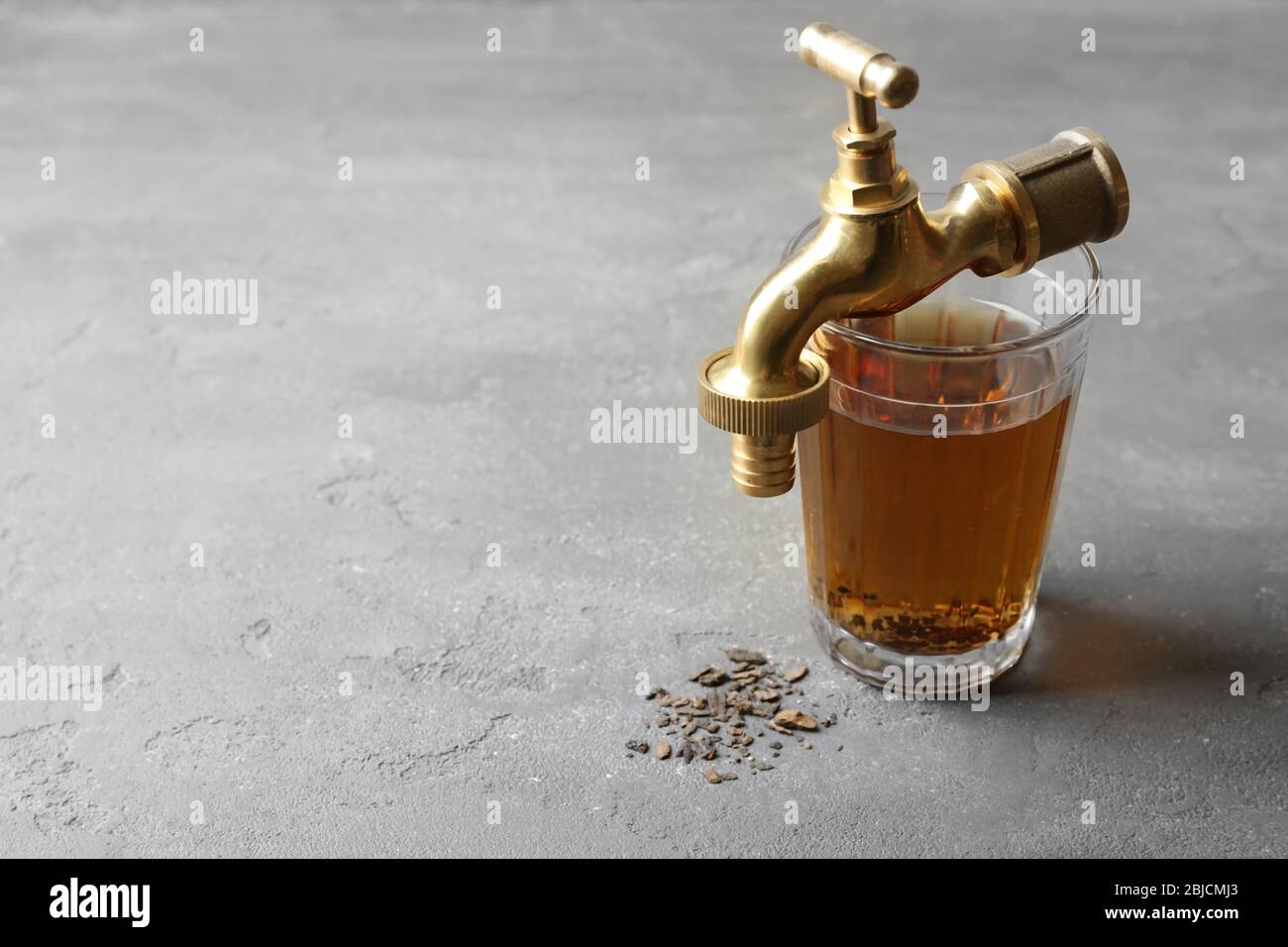 Faucet with glass of dirty water and rust flakes on gray textured ...