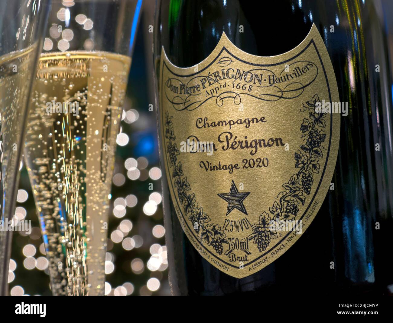 Dom Perignon Champagne bottle and poured glass of champagne in party atmosphere with sparkling lights in background Concept label post-dated to 2020 Stock Photo