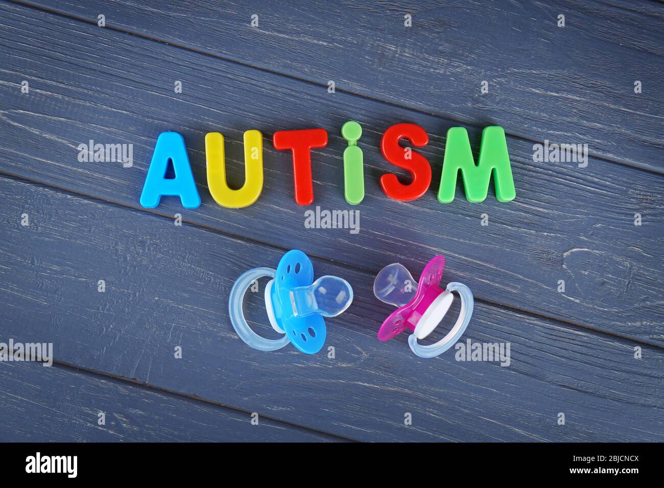 Word AUTISM with pacifiers on wooden background Stock Photo Alamy