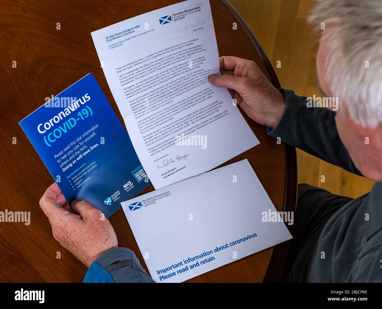 Scotland, United Kingdom. 29th April 2020. Coronavirus letter from First Minister Nicola Sturgeon, Scottish Government, and NHS information leaflet sent to all homes in the country received today A senior man reads the letter and pamphlet Stock Photo