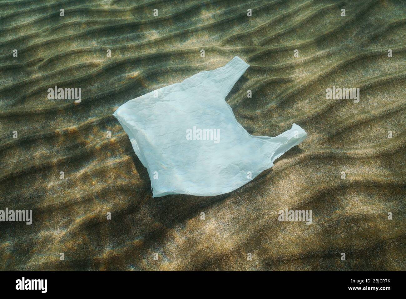 Plastic pollution in the ocean, a white plastic bag underwater on a sandy bottom Stock Photo