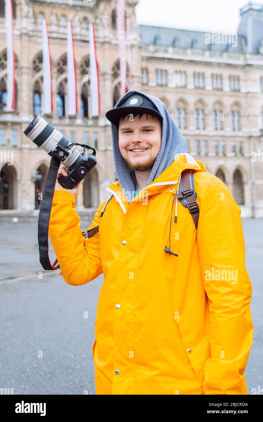man in yellow raincoat with big dslr camera at city square Stock Photo Alamy
