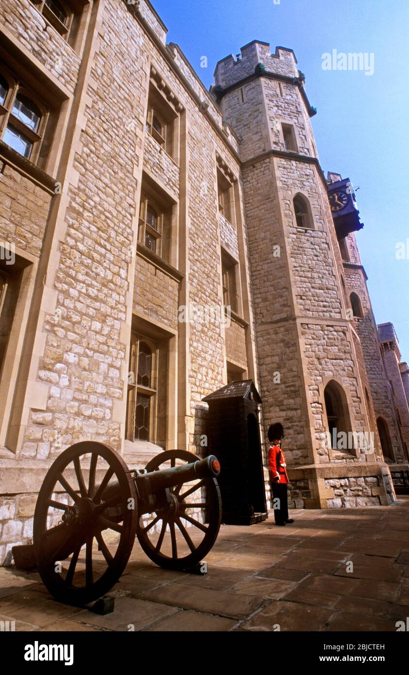 TOWER OF LONDON CROWN JEWELS HOUSE GRENADIER GUARD BUSBY ceremonial guard in traditional red tunic and busby on guard at the Crown Jewels House with cannon field gun in foreground at the Tower of London LONDON UK Stock Photo