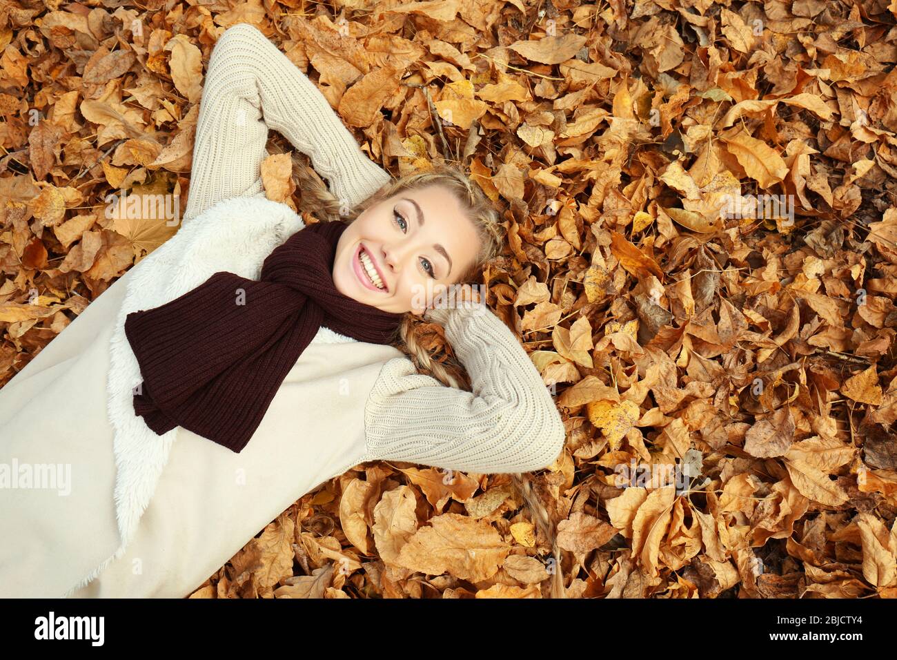 Beautiful girl lying on leaves in autumn park Stock Photo - Alamy
