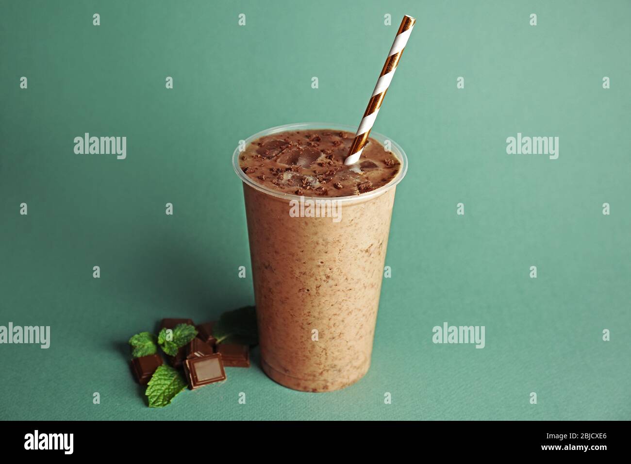 https://c8.alamy.com/comp/2BJCXE6/tasty-chocolate-milkshake-in-plastic-cup-on-green-background-2BJCXE6.jpg
