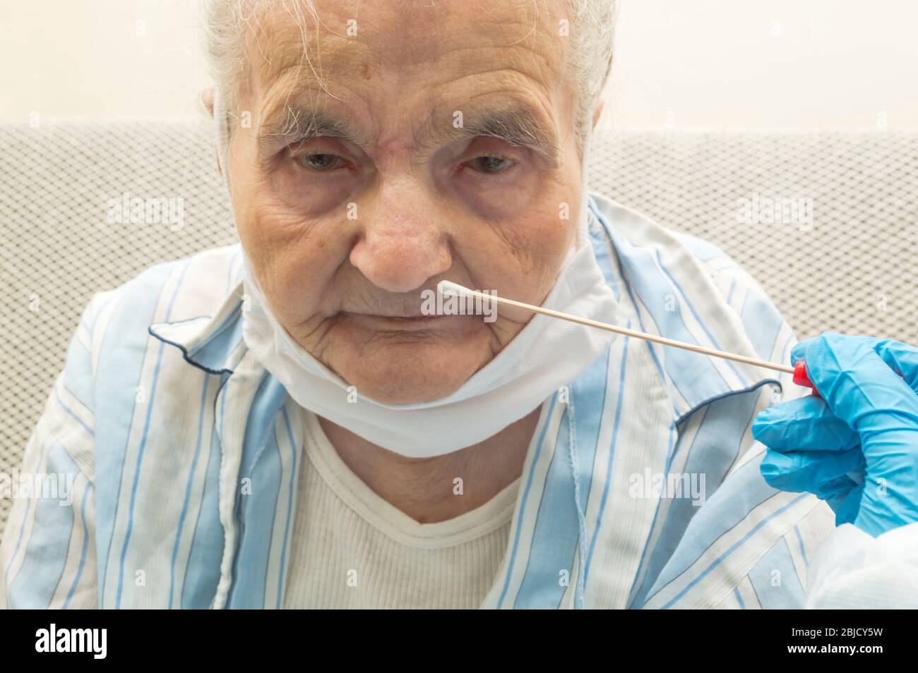 Coronavirus test - Medical worker taking a throat swab for coronavirus sample from a potentially infected elderly women Stock Photo
