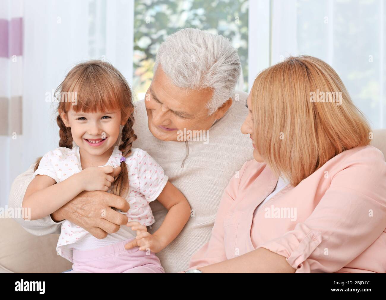 Grandparents with granddaughter on couch Stock Photo