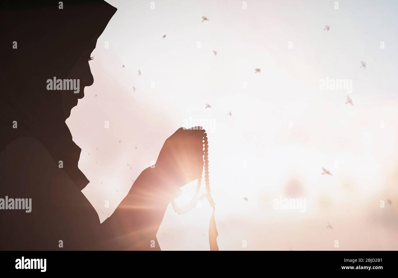 Young female muslim prayer with hijab praying to God front of white