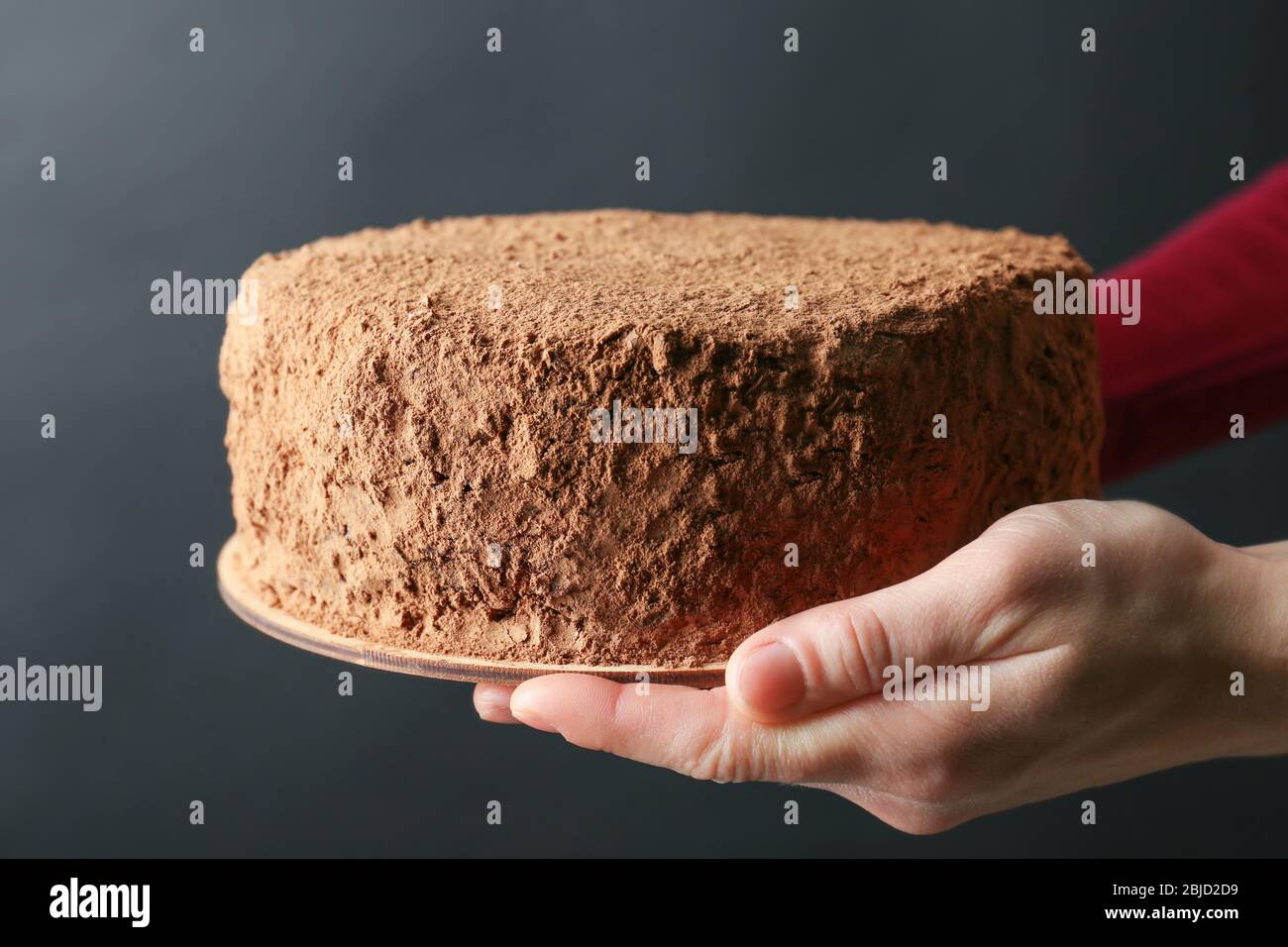Woman holding chocolate cake on dark background Stock Photo