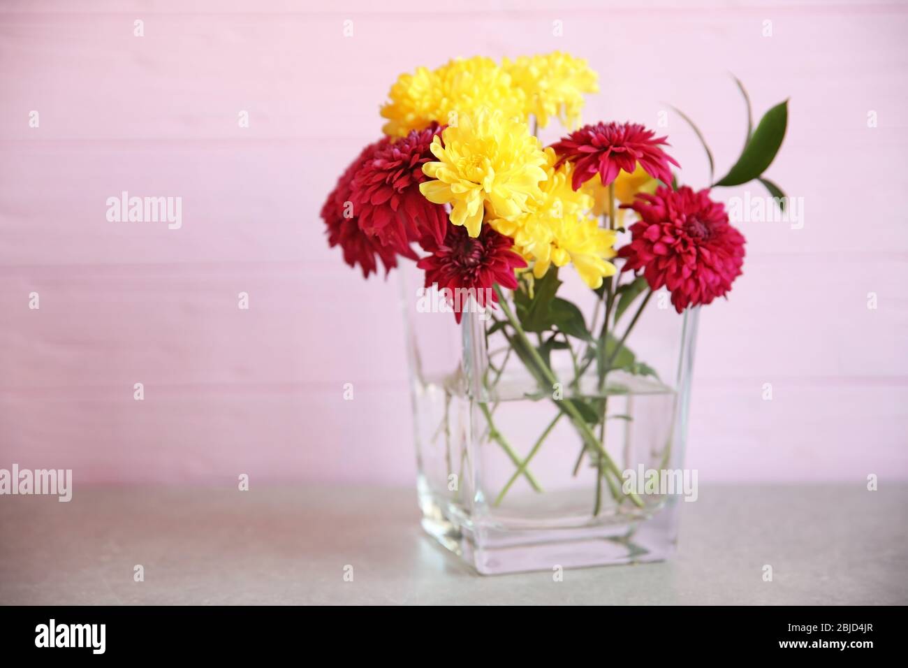 Glass vase with bouquet of beautiful flowers on color background Stock