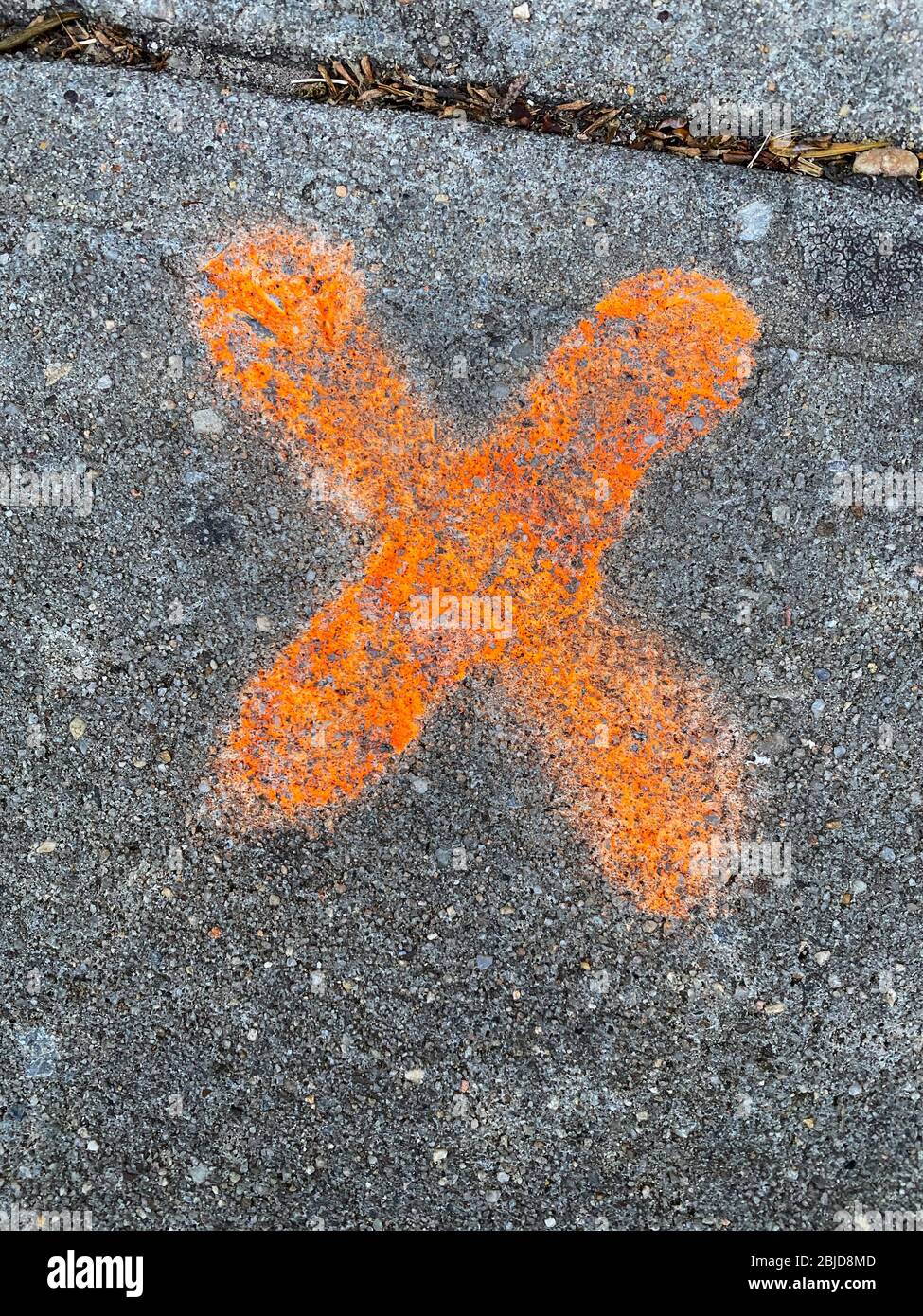 A bright orange X used as a marking device on a sidewalk in Brooklyn