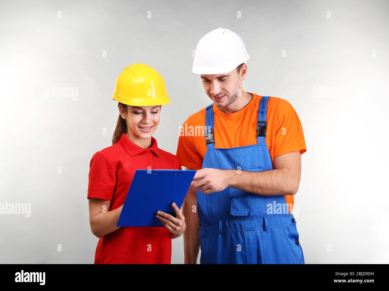 Warehouse workers with clipboard discussing something, on light background Stock Photo