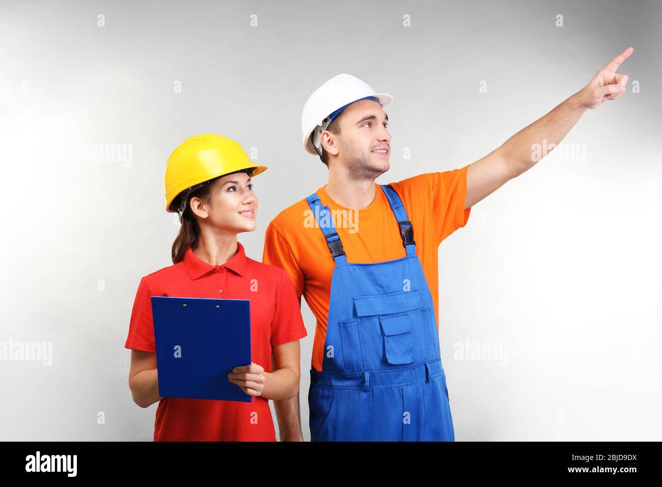 Warehouse workers with clipboard discussing something, on light background Stock Photo