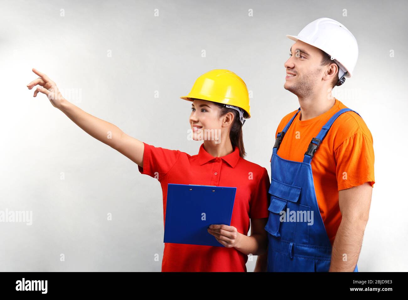 Warehouse workers with clipboard discussing something, on light background Stock Photo