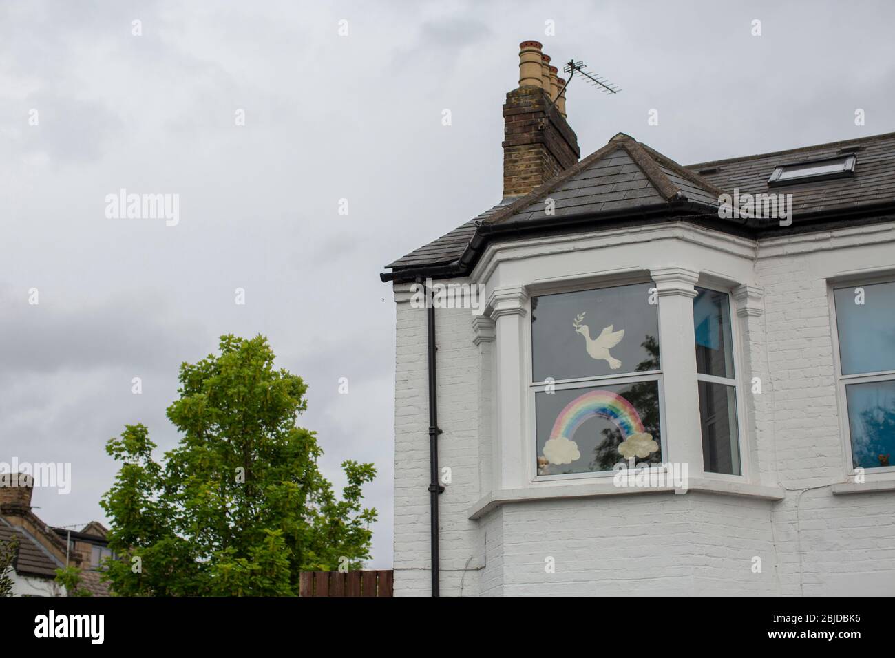 West Norwood, UK. 29th April, 2020.  Life In South London During The Coronavirus Lockdown. A cut out drawing of a white dove and a rainbow in a window of an end of terrace house in West Norwood, London. ( Credit: Sam Mellish/Alamy Live News ) Stock Photo