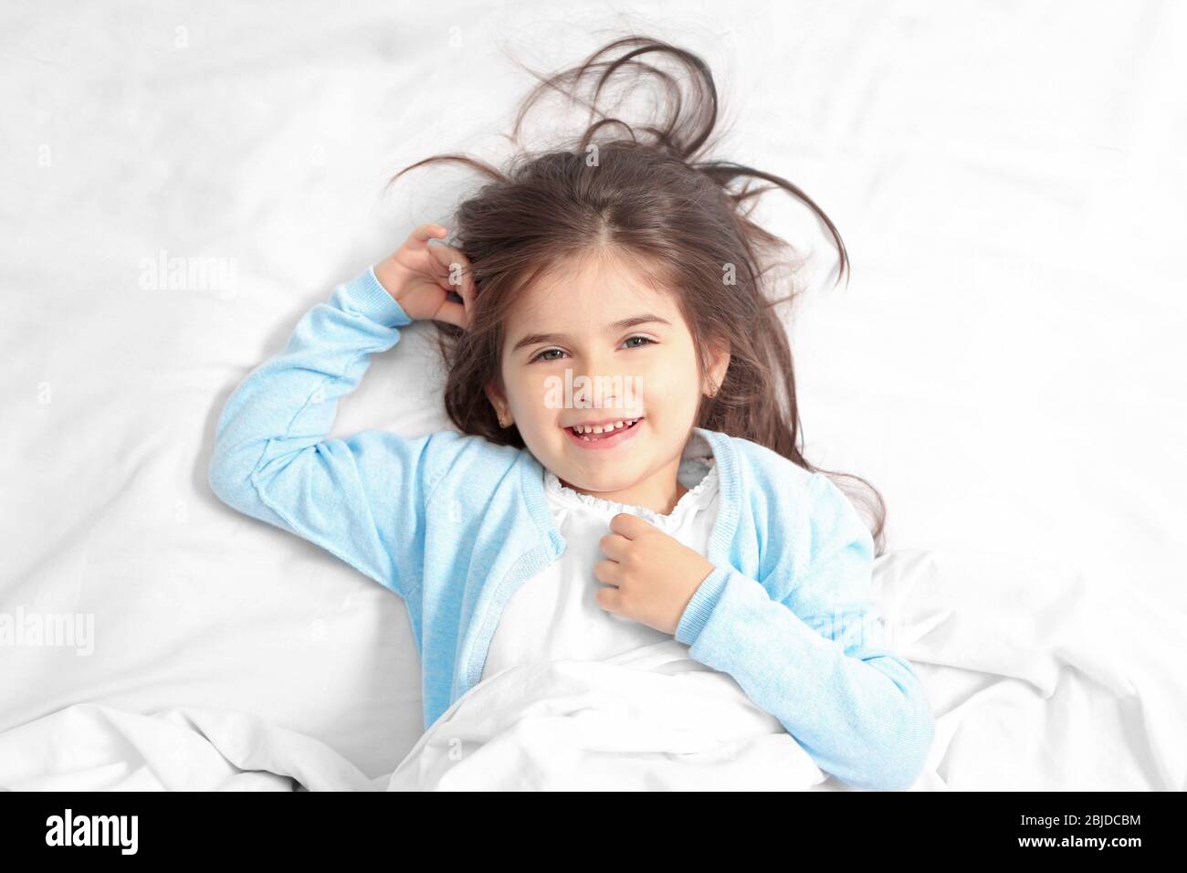Cute little girl lying in bed at home Stock Photo - Alamy