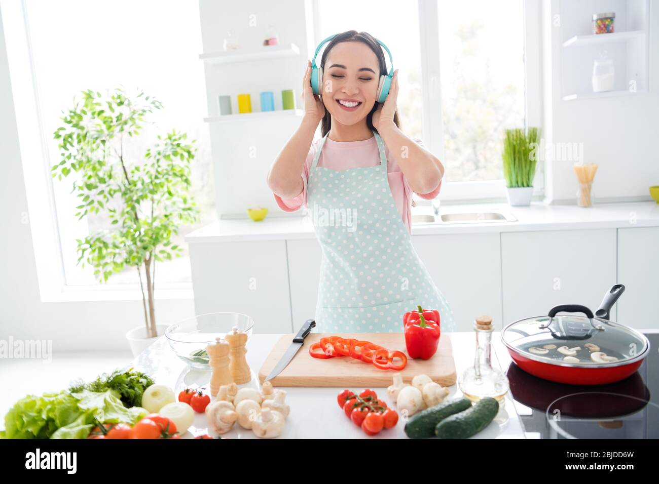 Young beautiful girl in panties and t-shirt listening to music in the  kitchen and cooking. Young female with headphones on the kitchen. Stock  Photo by ©flowertiare 153509830