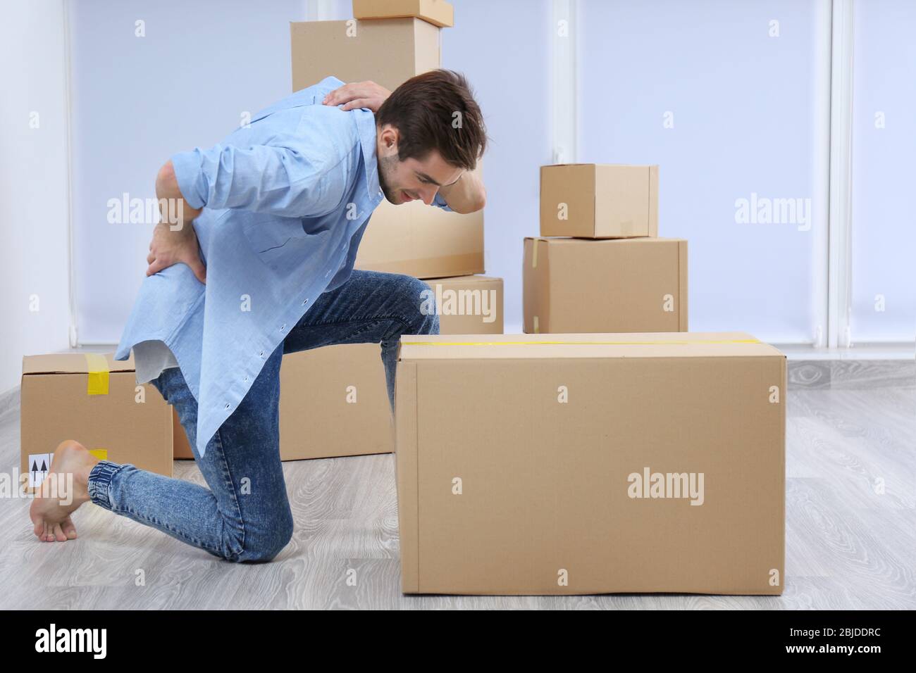 Man suffering back ache moving boxes indoors Stock Photo - Alamy