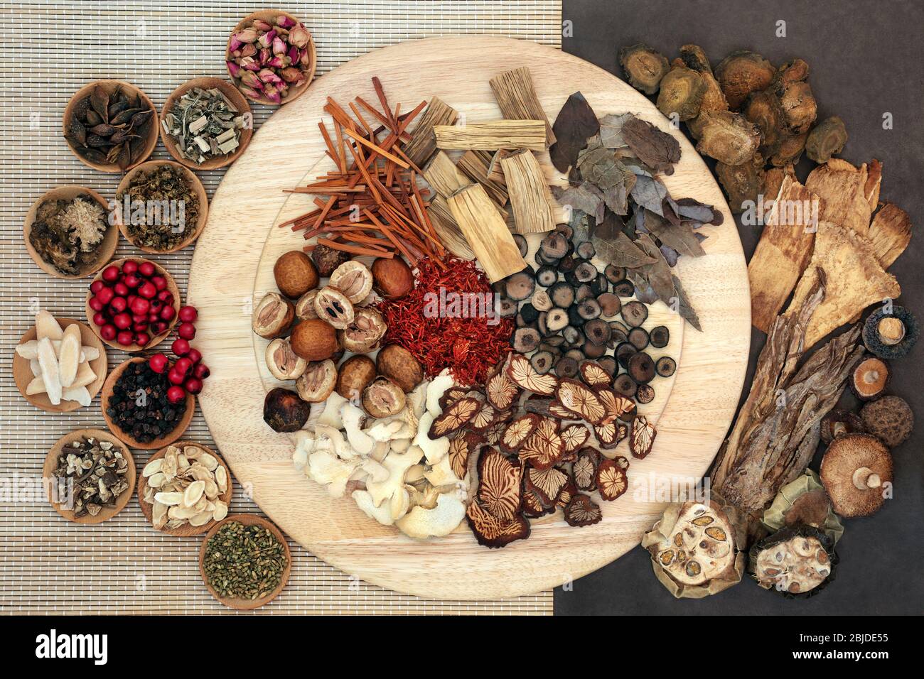 Chinese herbs & spice used in traditional herbal medicine on a wooden board, bamboo & lokta