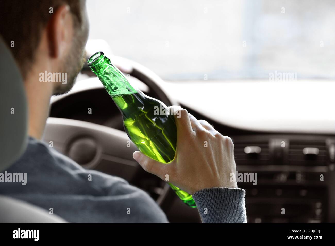 Man drinking beer while driving car, closeup. Don't drink and drive