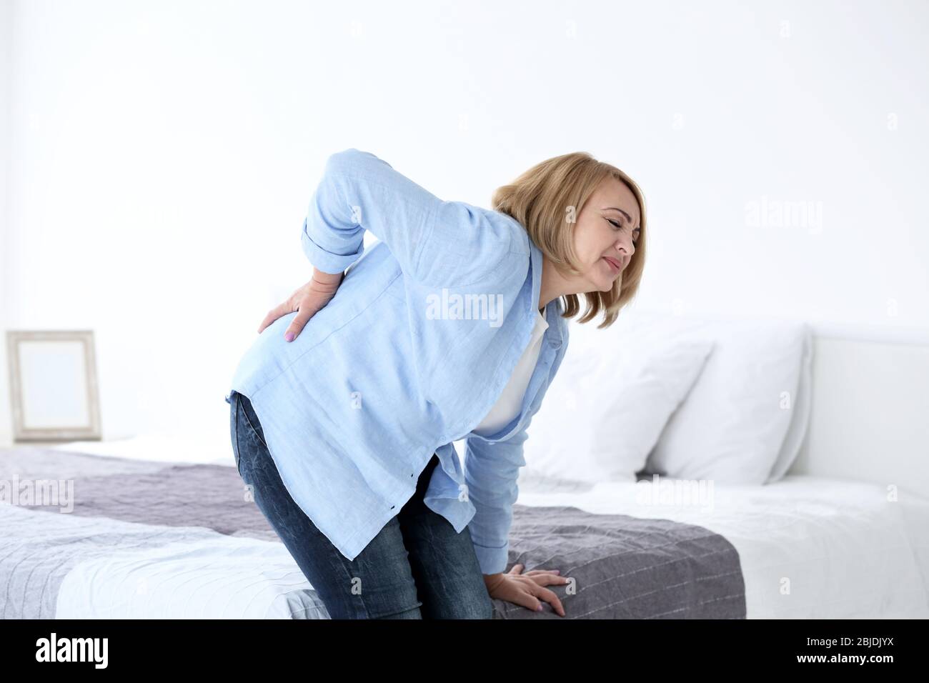 Senior woman suffering from backache at home Stock Photo - Alamy