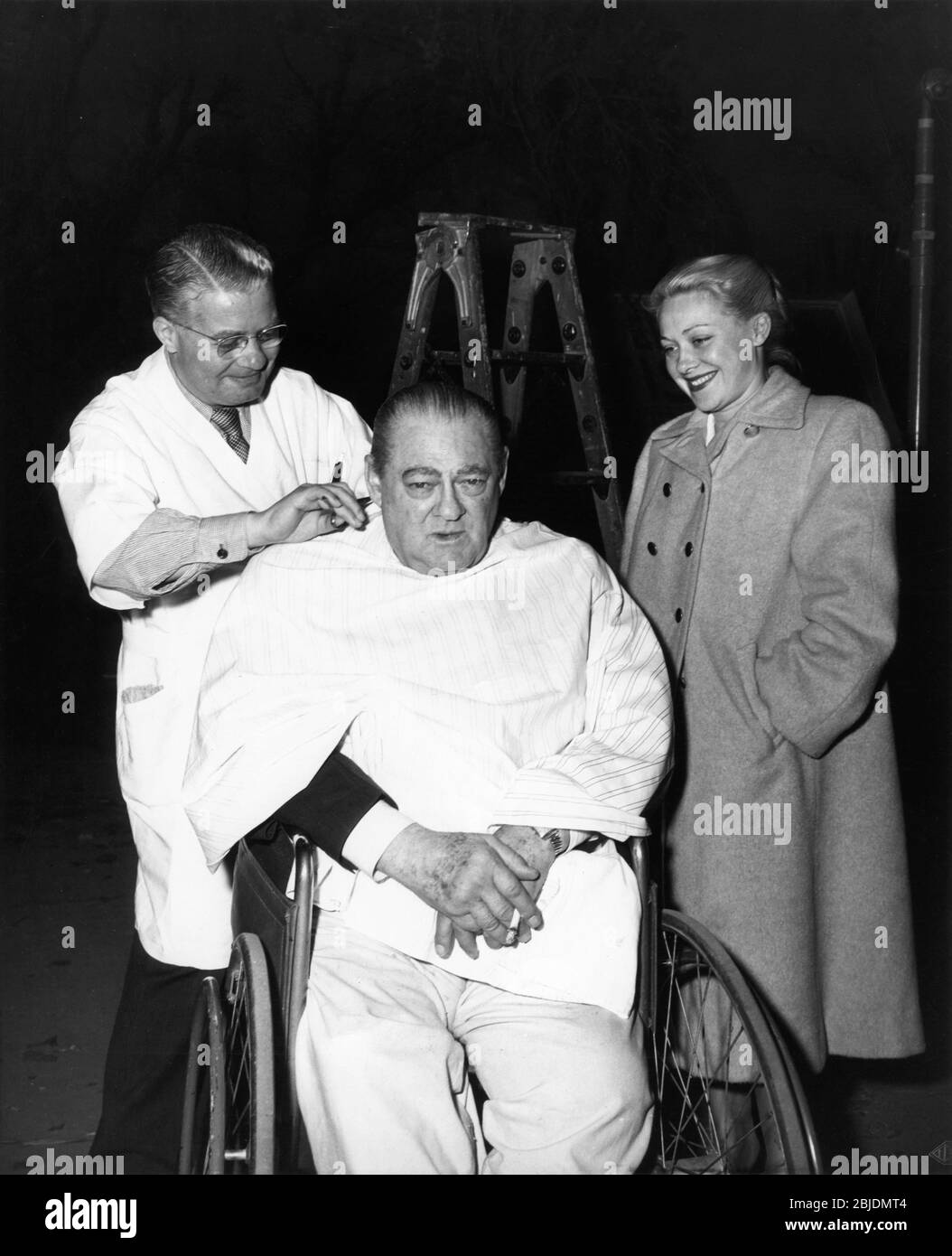 LIONEL BARRYMORE gets a haircut from Studio Barber WALTER HORN as Hairdresser BETTE LOU DELMONT watches on set candid during filming of KEY LARGO 1948 director JOHN HUSTON screenplay RICHARD BROOKS and JOHN HUSTON based on the play by MAXWELL ANDERSON Warner Bros. Stock Photo
