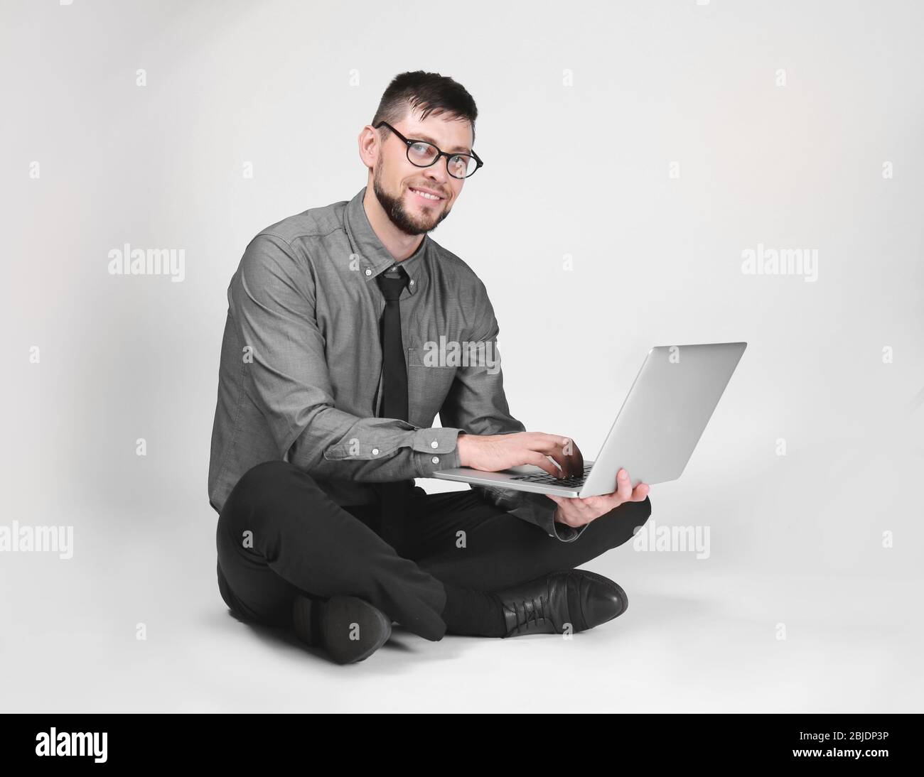 Handsome young programmer with laptop on light background Stock Photo