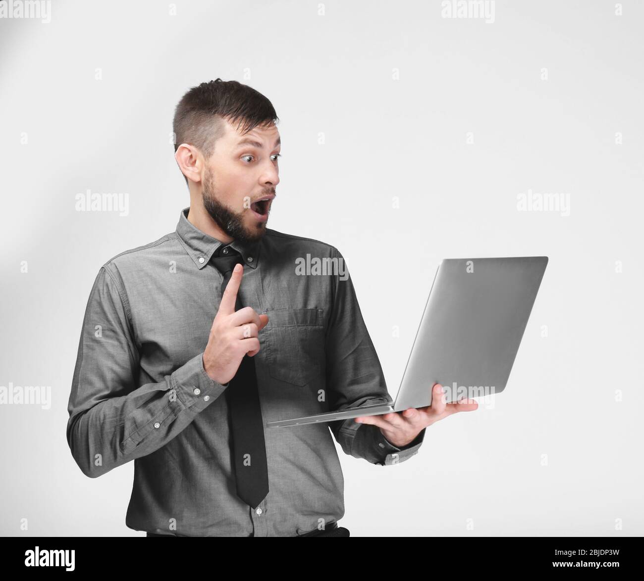 Handsome young programmer with laptop on color background Stock Photo