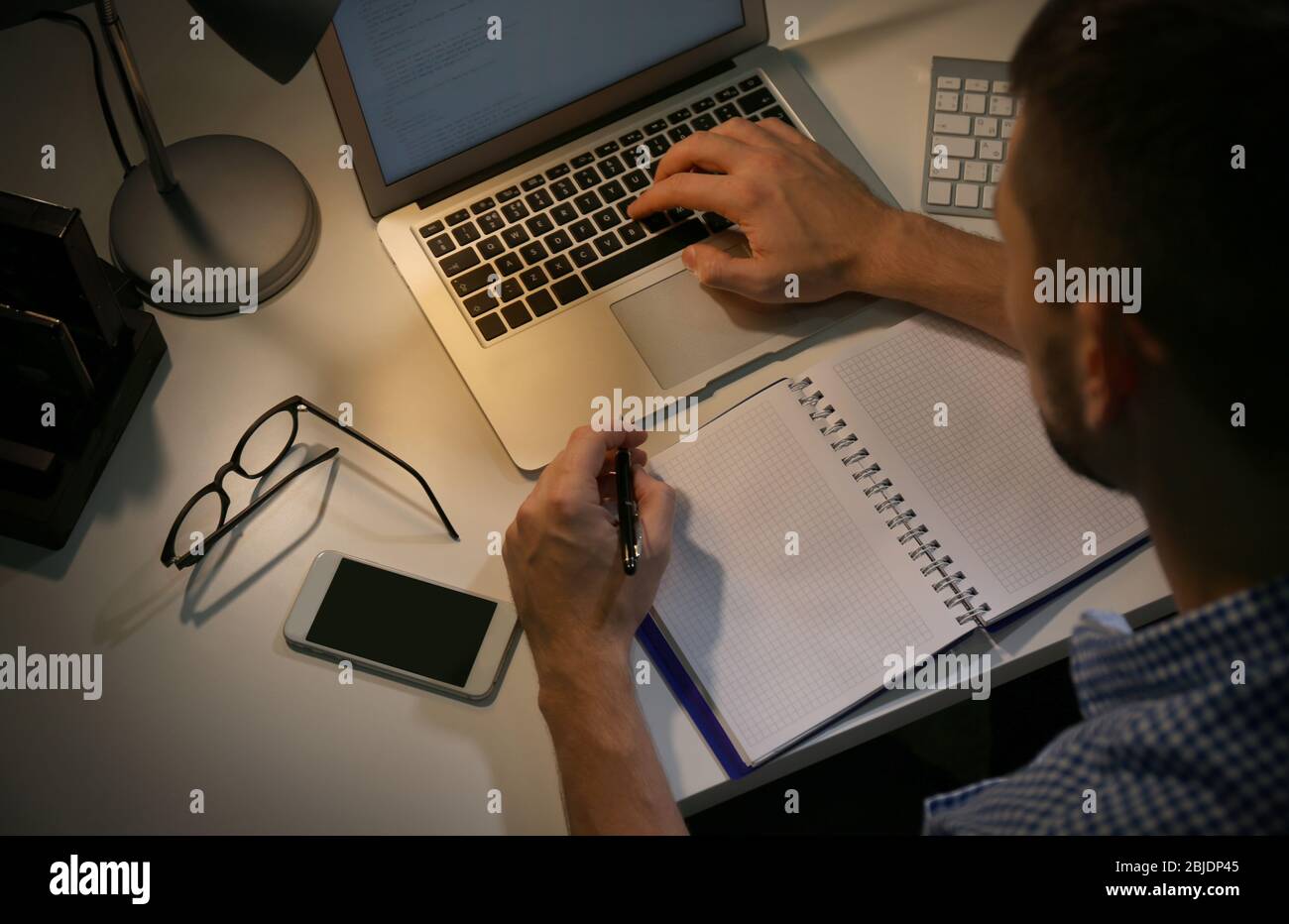 Young programmer working at home late in evening Stock Photo