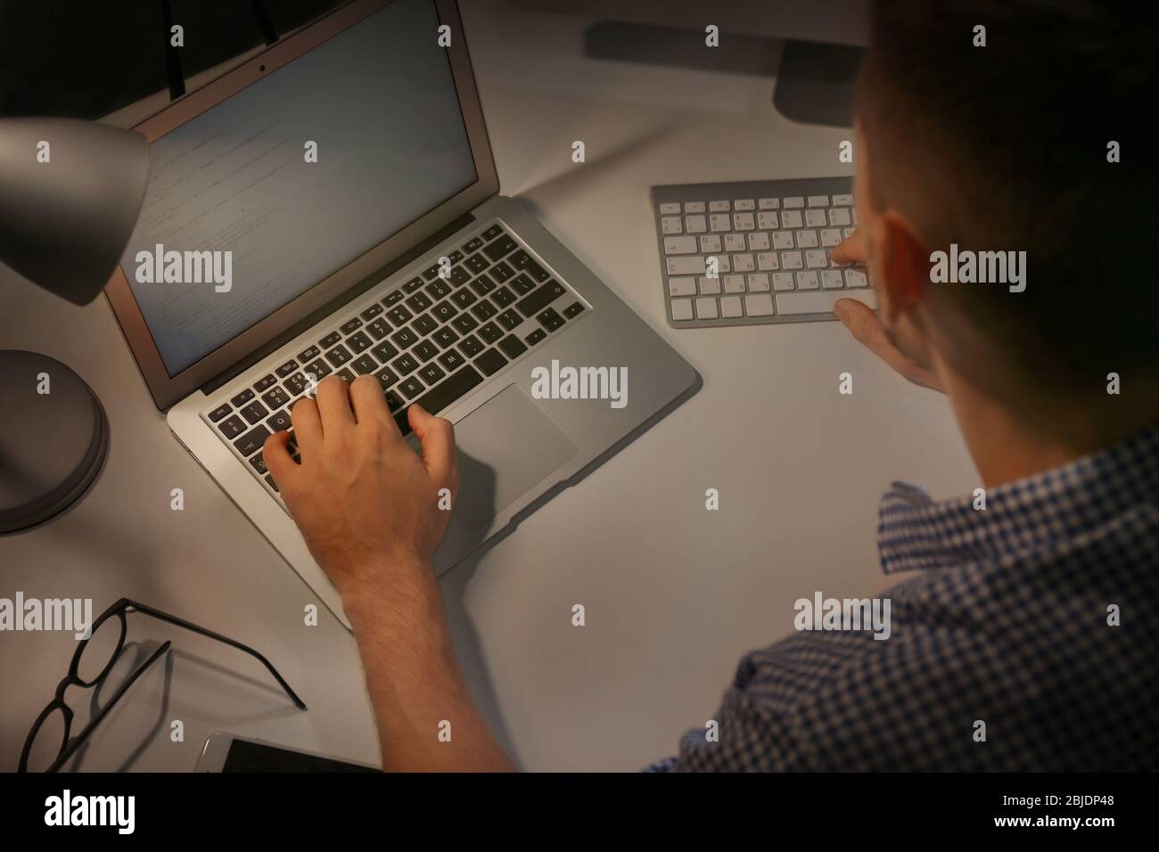 Young programmer working at home late in evening Stock Photo