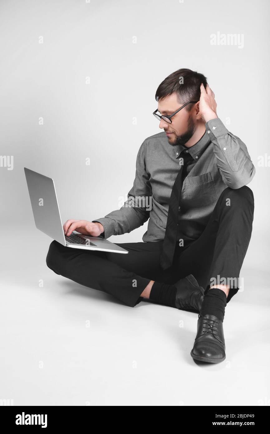 Handsome young programmer with laptop on light background Stock Photo