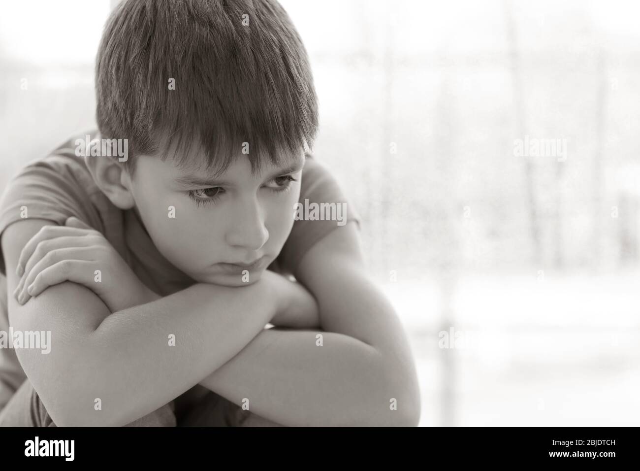 Sad little boy sitting on windowsill Stock Photo - Alamy
