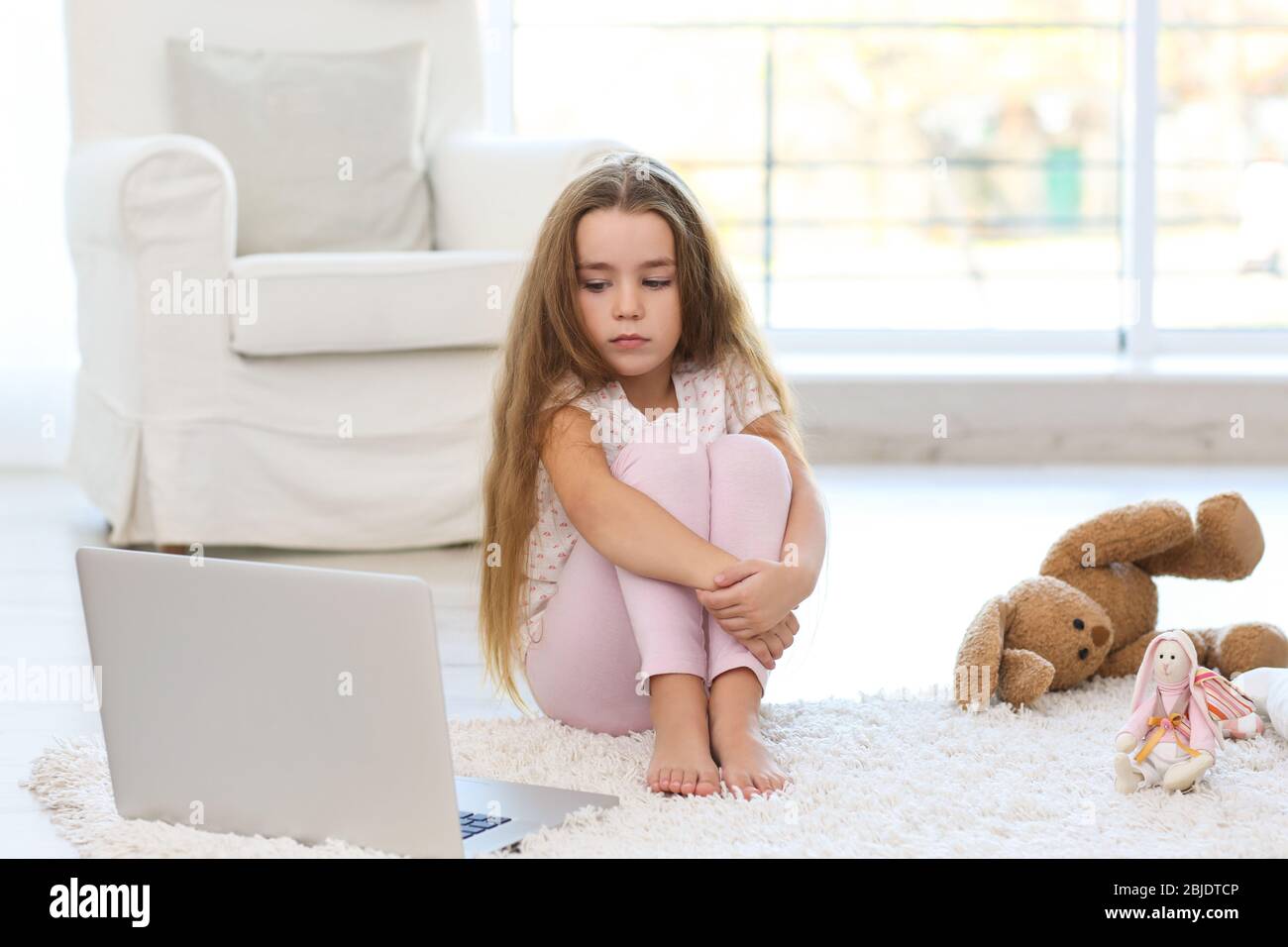 Sad little girl sitting on floor in room Stock Photo - Alamy
