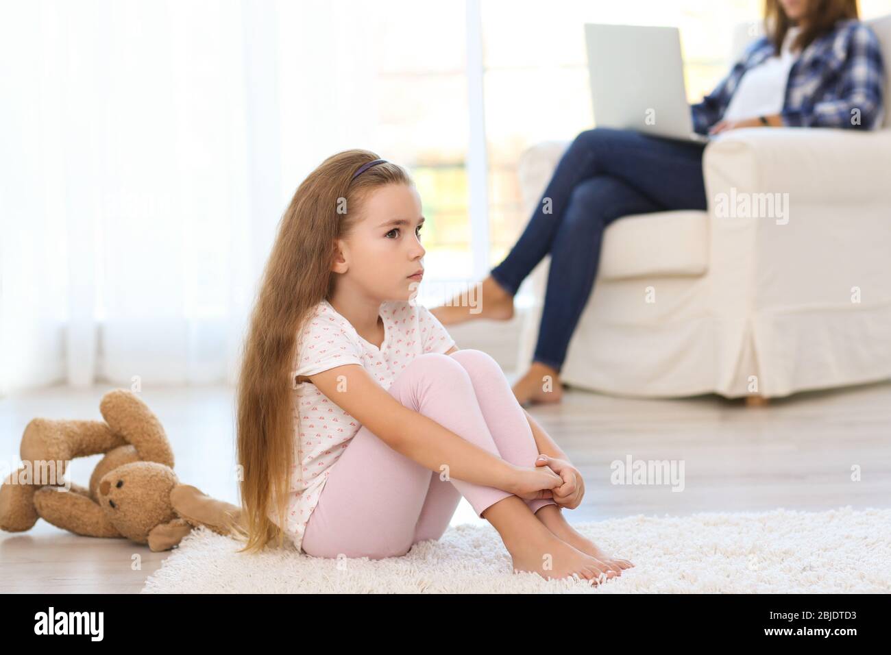 Sad little girl sitting on floor in room Stock Photo - Alamy