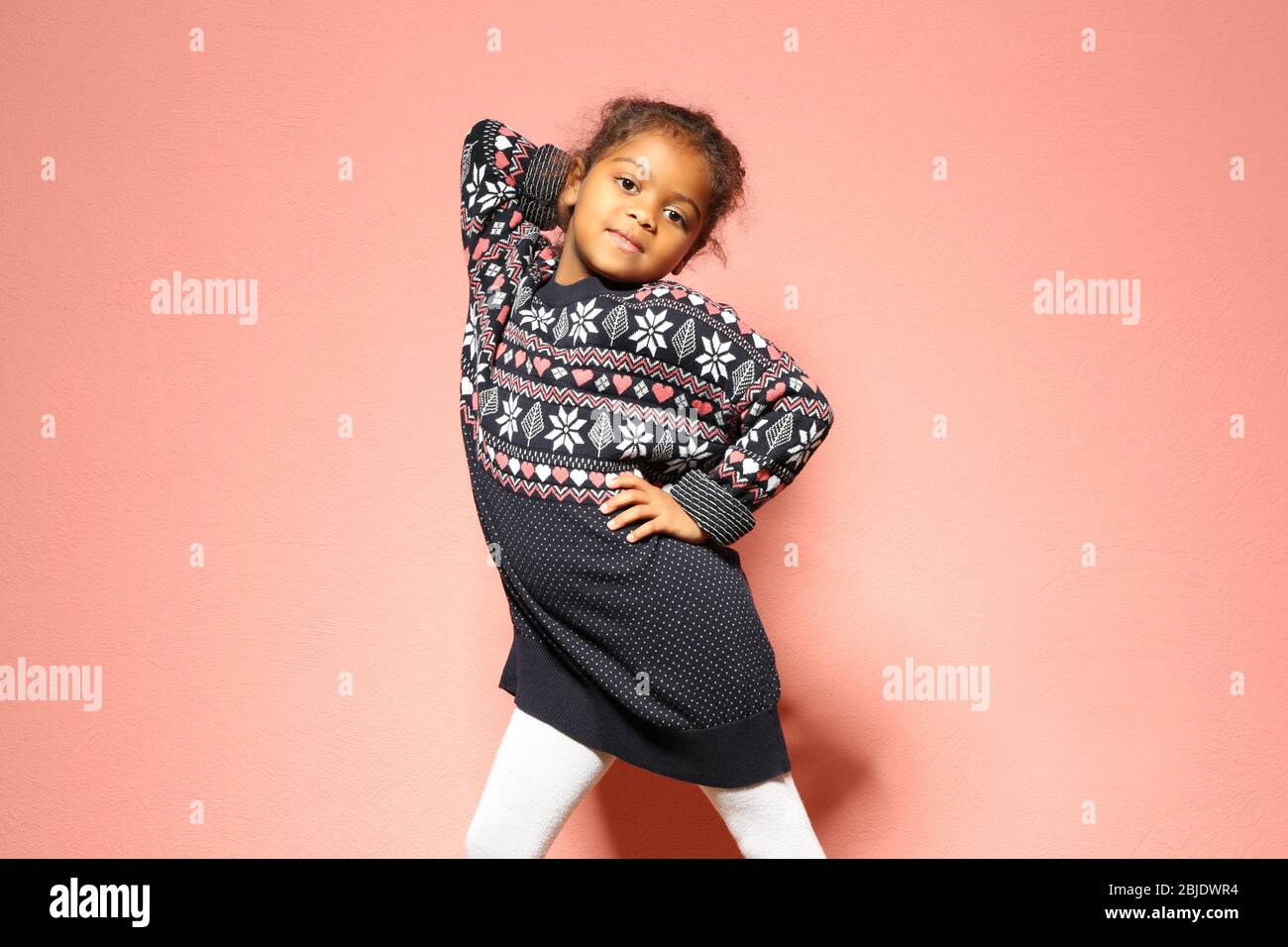 Cute little African American girl in dress against pink wall. Fashion ...