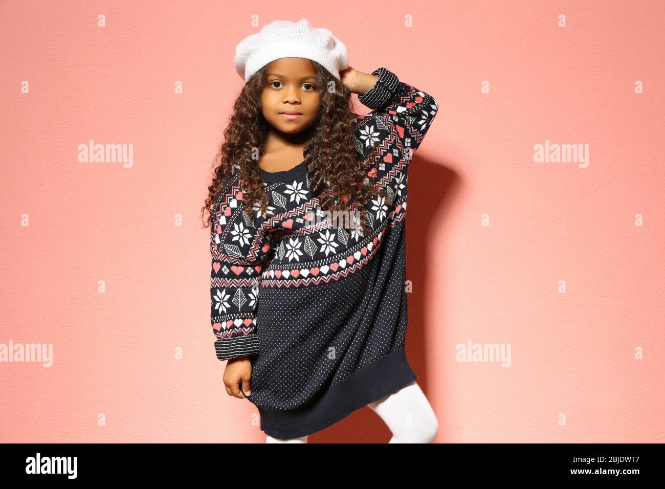 Cute little African American girl in dress against pink wall. Fashion ...
