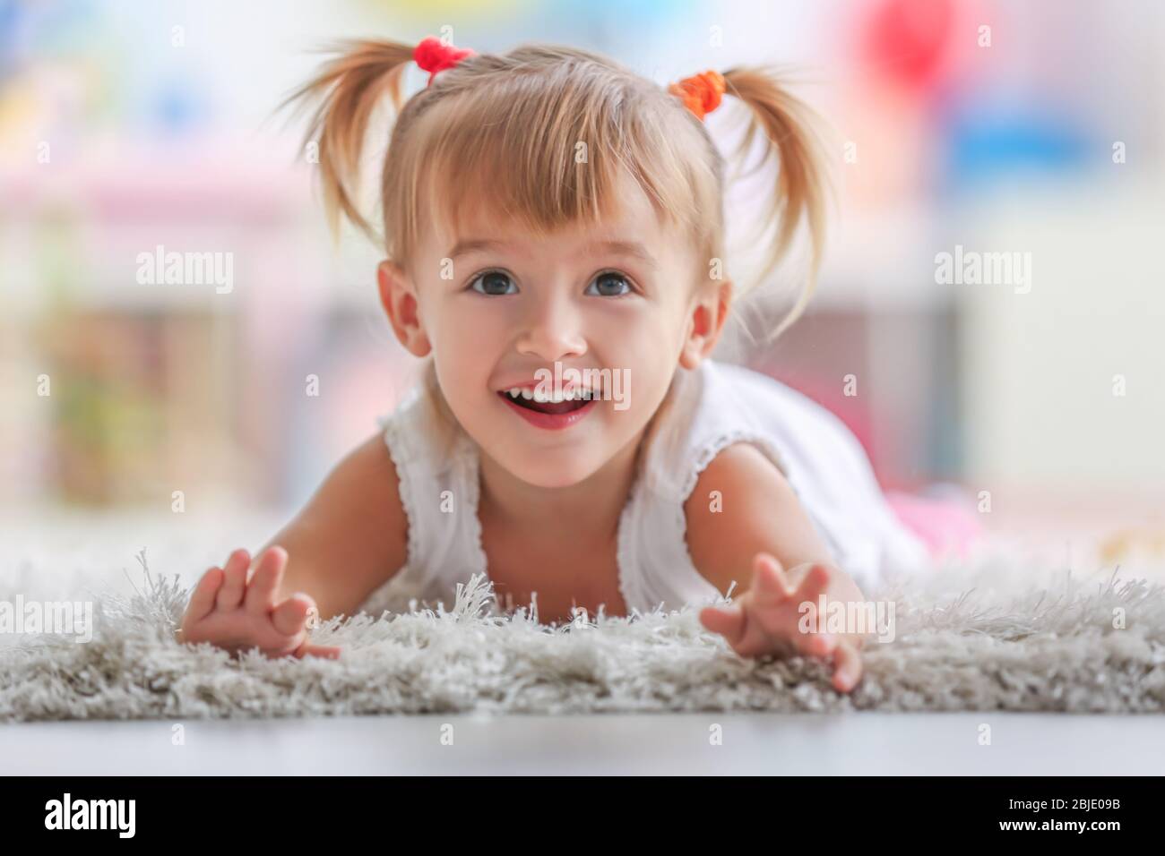 Cute little girl lying on carpet at home Stock Photo Alamy