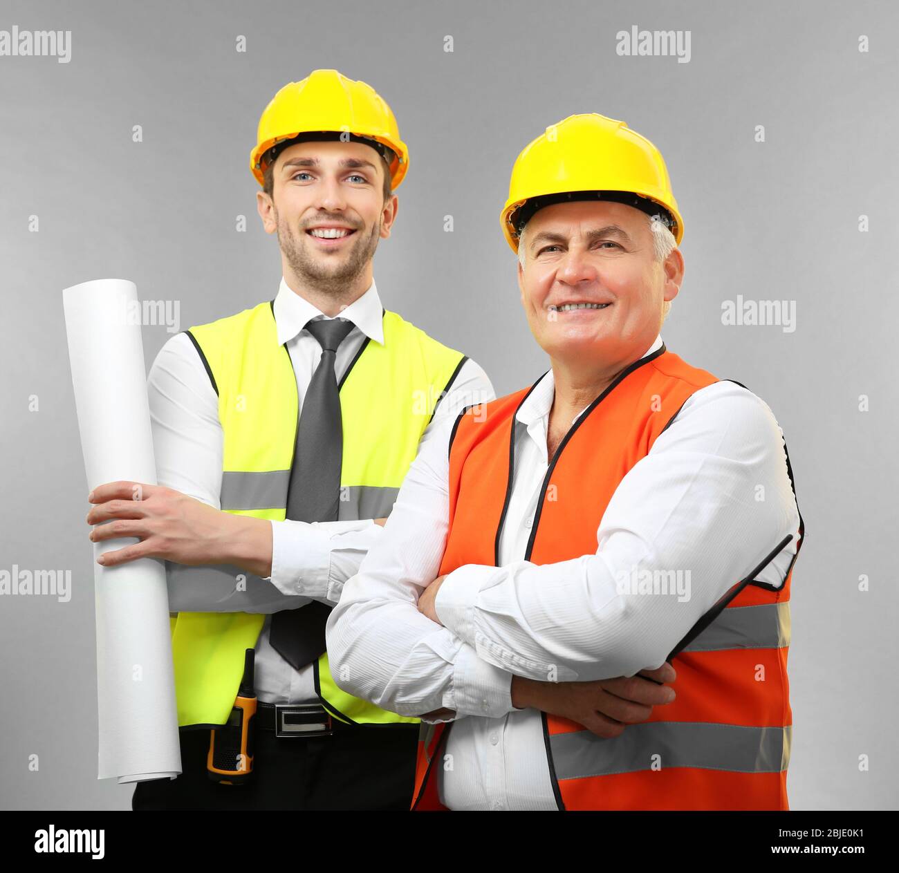 Handsome engineer and senior worker on light background Stock Photo