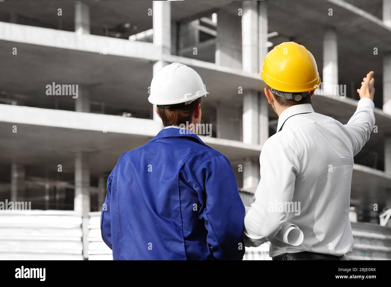 Engineer and worker discussing construction of unfinished building Stock Photo