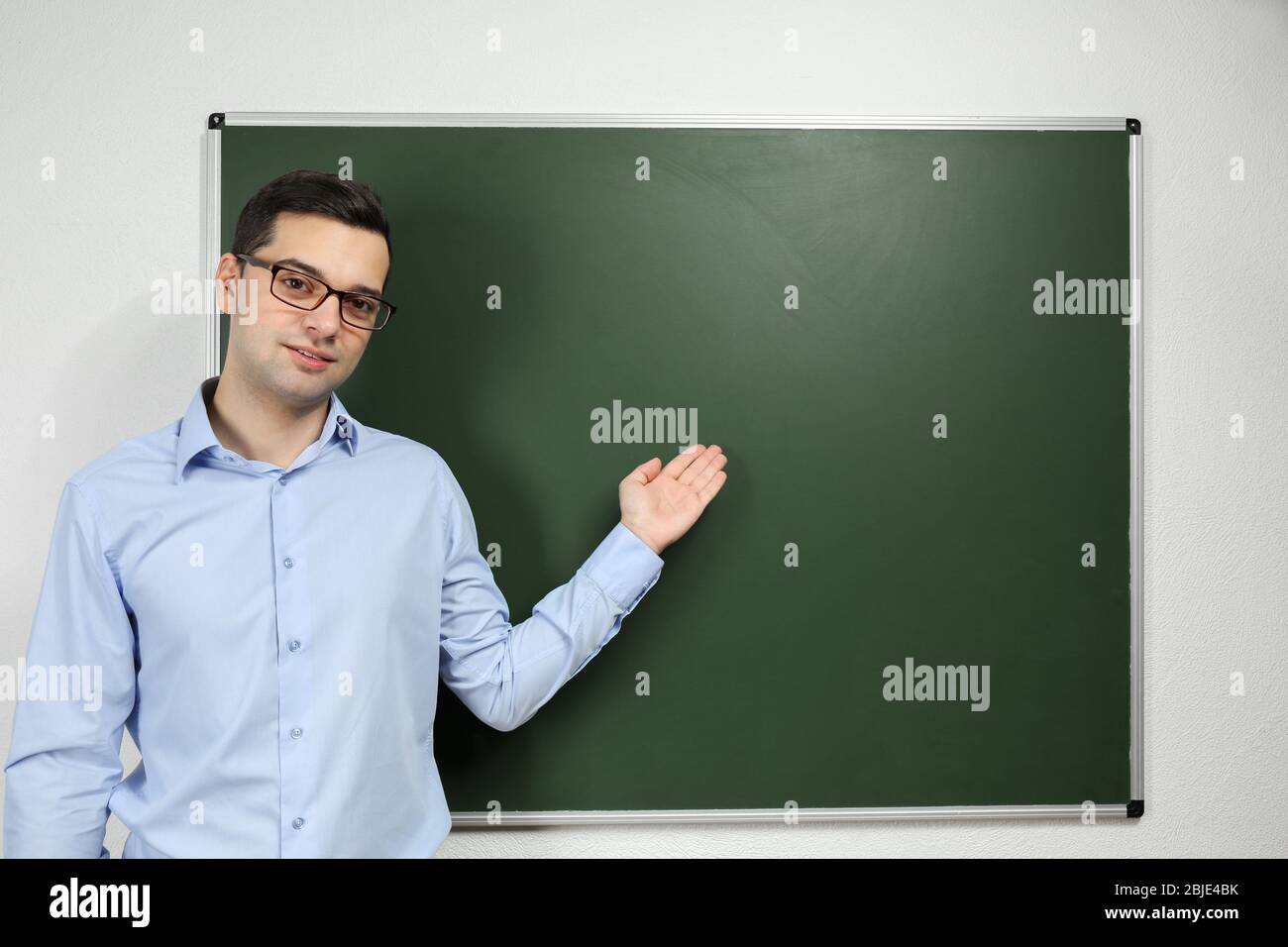 Handsome young teacher standing near blackboard in classroom Stock ...