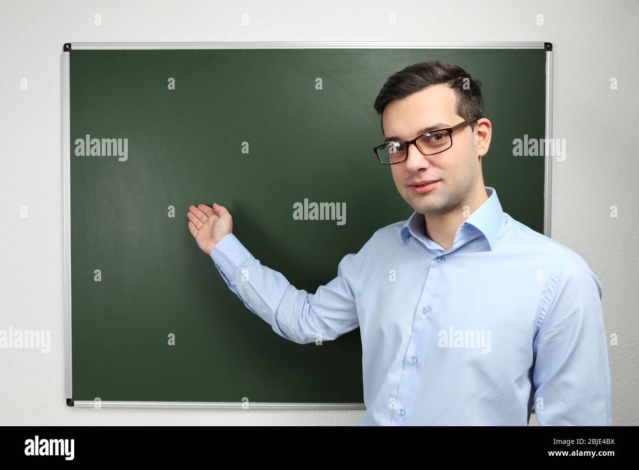 Handsome young teacher standing near blackboard in classroom Stock ...