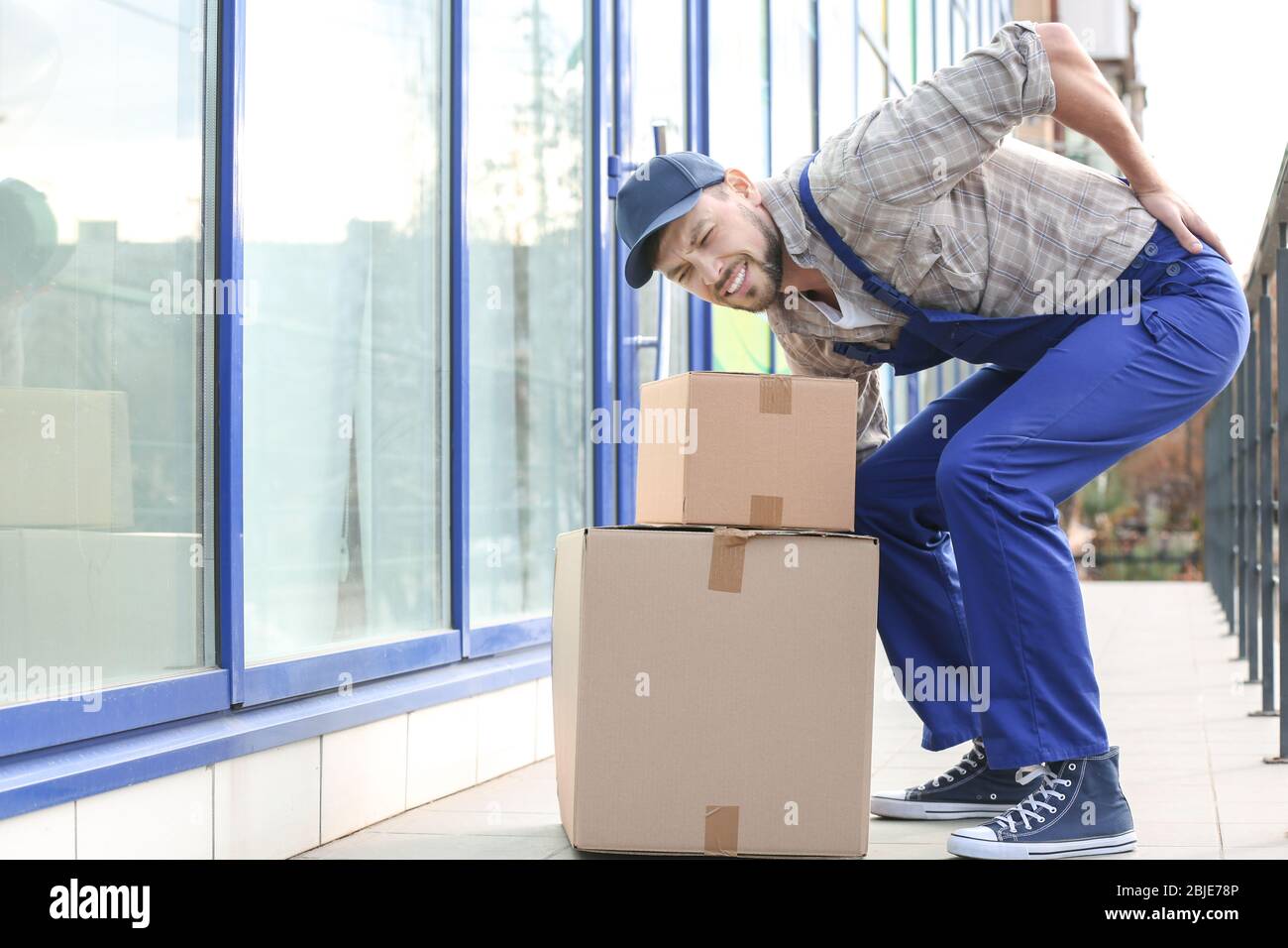 Man suffering from back ache while moving boxes Stock Photo - Alamy