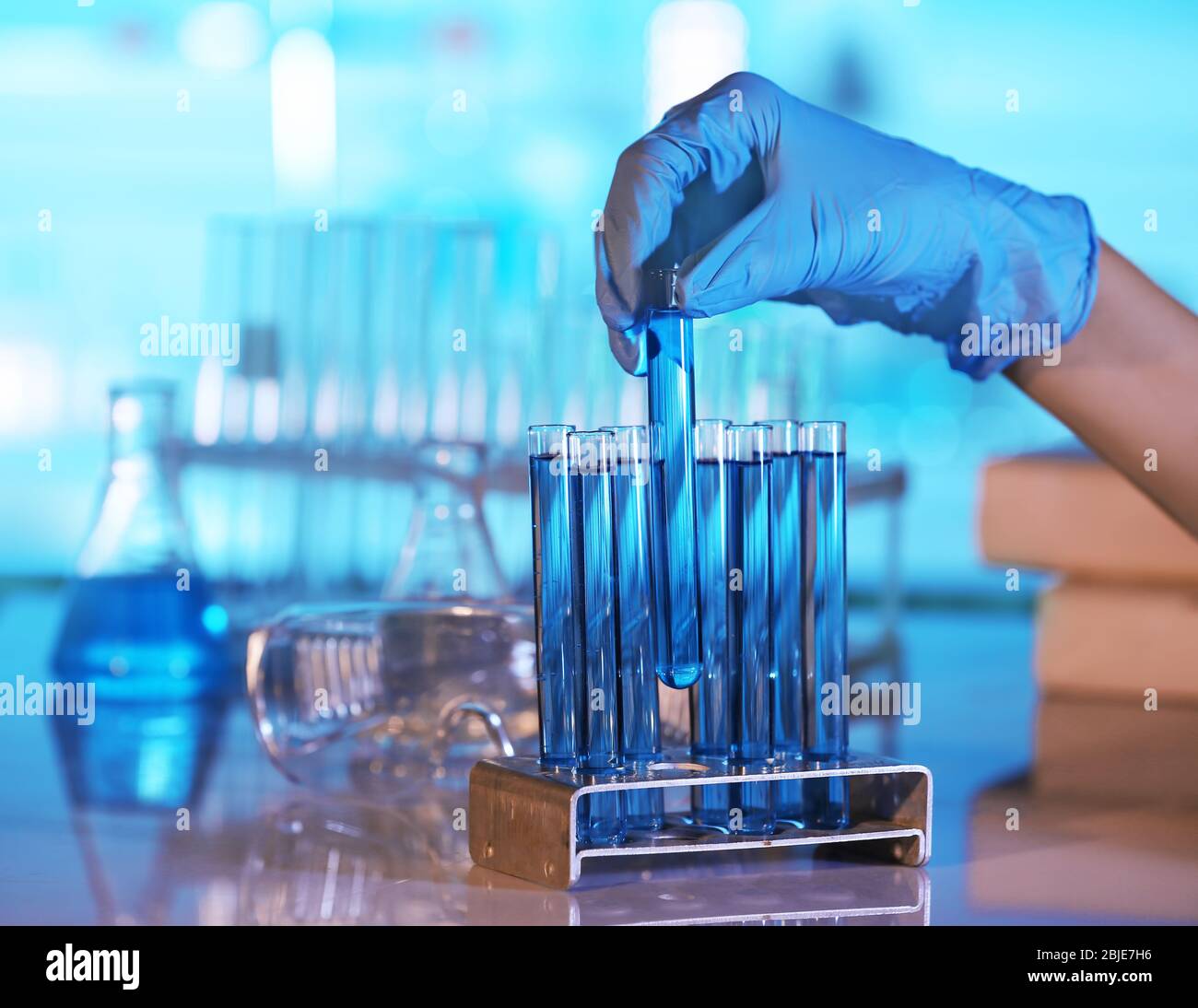 Hand in glove holding test tube on blurred background Stock Photo - Alamy