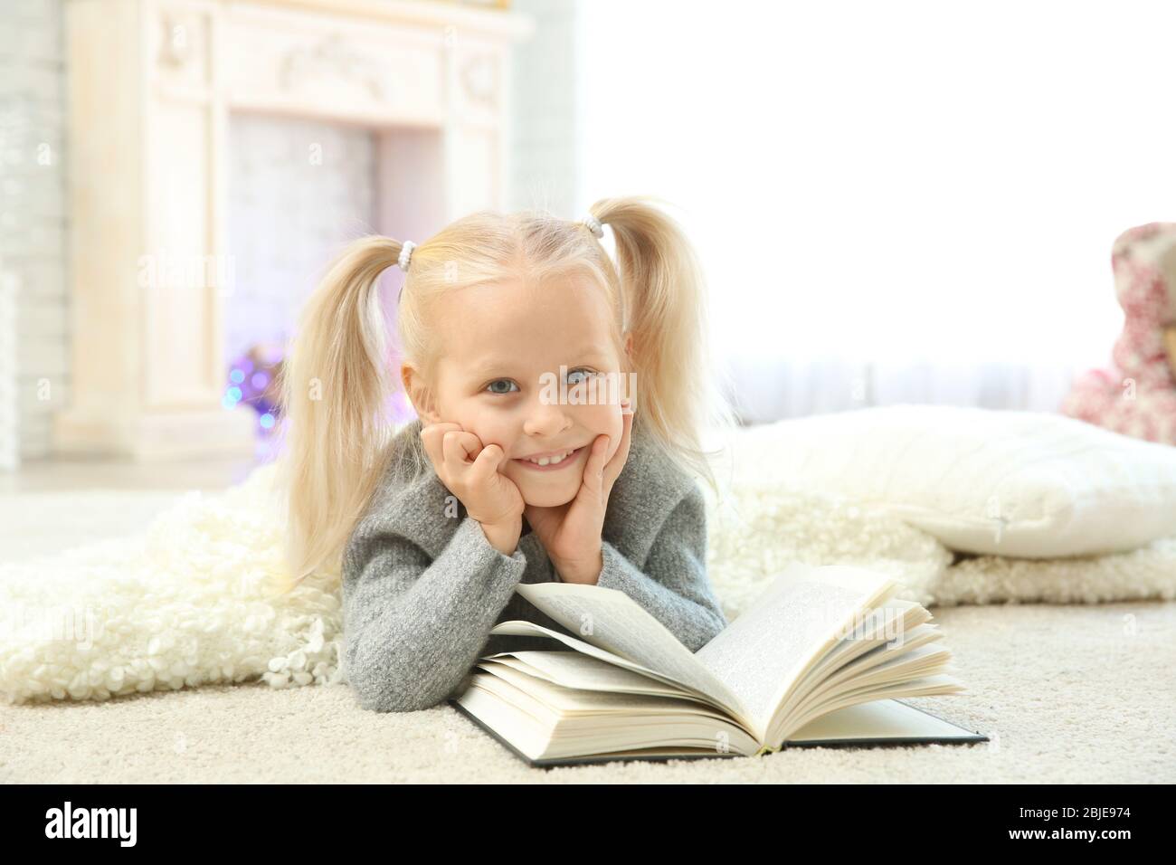 Cute little girl reading book at home Stock Photo - Alamy
