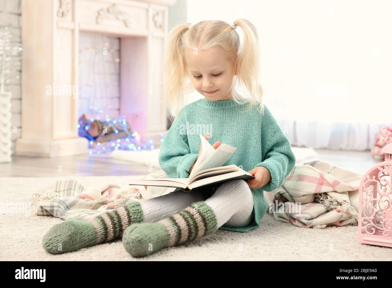 Cute little girl reading book at home Stock Photo - Alamy