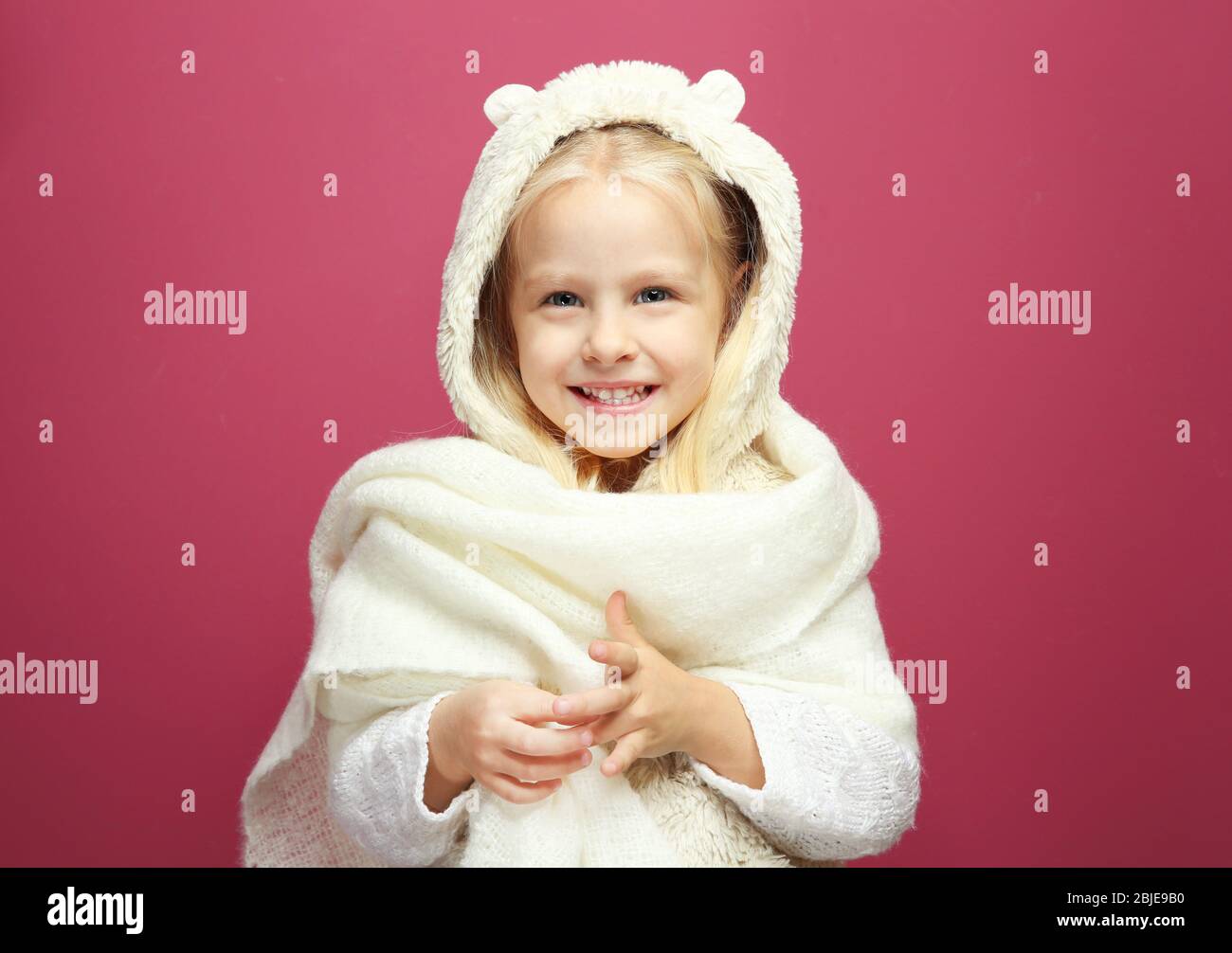 Funny little girl in warm clothes on color background Stock Photo