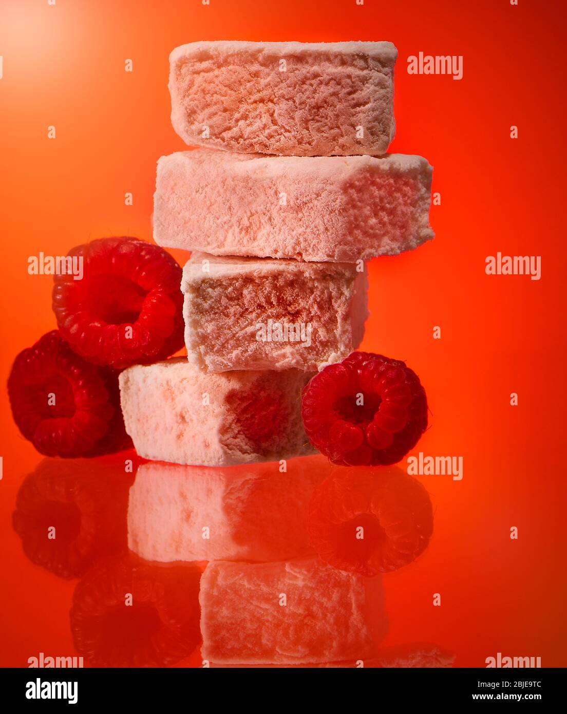 Luxury raspberry marshmallows photographed on a red background in the studio. Stock Photo