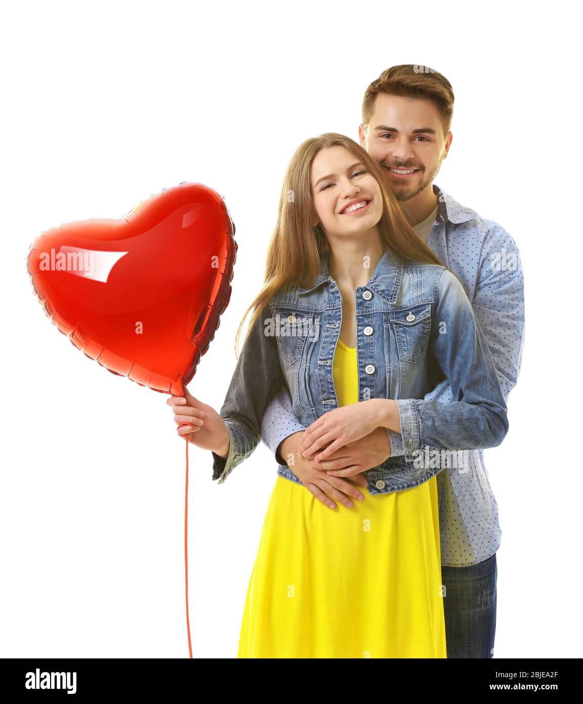 Cute young couple with balloon in shape of heart on white background ...