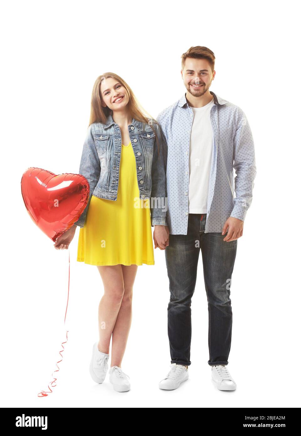 Cute young couple with balloon in shape of heart on white background ...