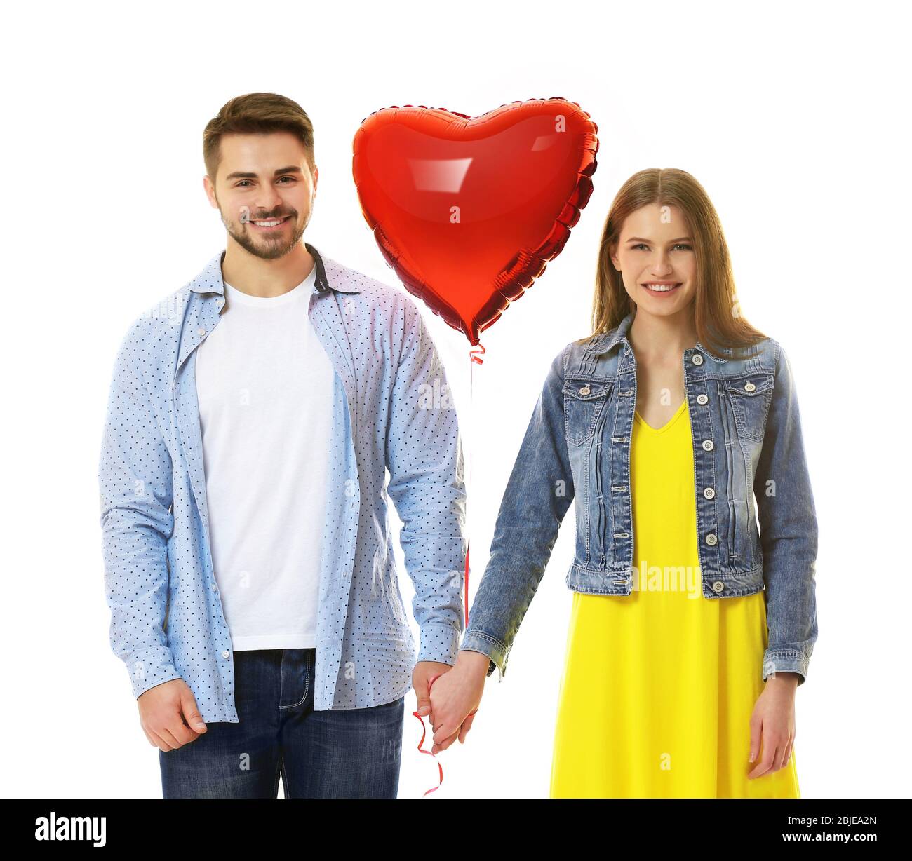 Cute young couple with balloon in shape of heart on white background ...